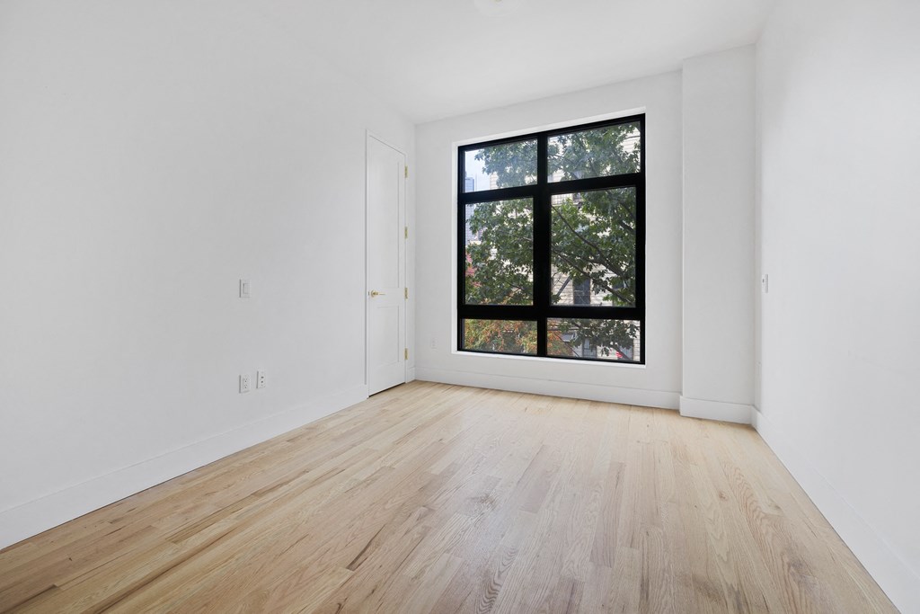 a room with white walls and a large window and wooden floors